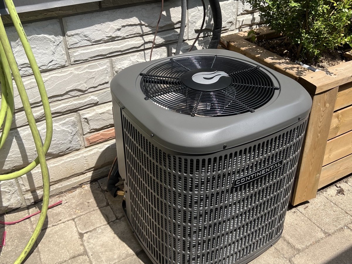 Outdoor central AC condenser serviced for cooling performance.
